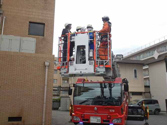 中学生と救助隊がはしご車に載っている写真