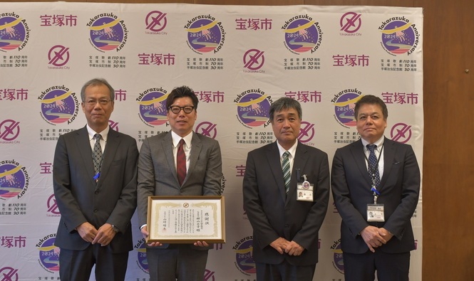 感謝状を持つアプローズ不動産販売原田部長と教育長、社会教育部長、西図書館長