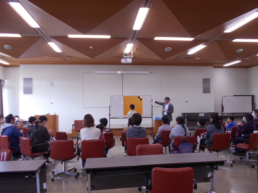 囲碁体験イベントで、講師のルール説明を参加者が聞いている写真