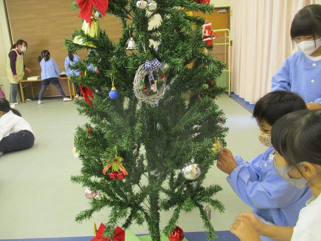 5歳児すみれ組がツリーの飾りつけをしている写真