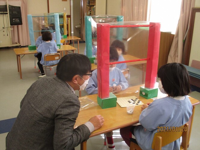 囲碁の先生に囲碁をしているところを見てもらっている子どもの写真