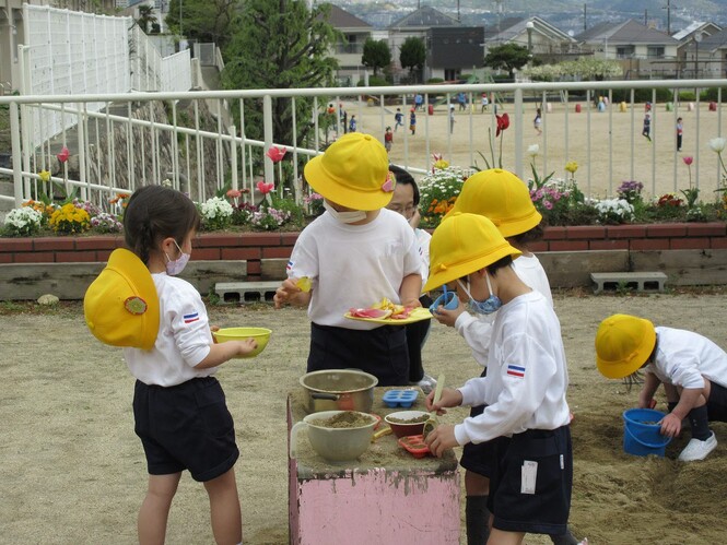 砂場でごちそうを作る子どもの写真