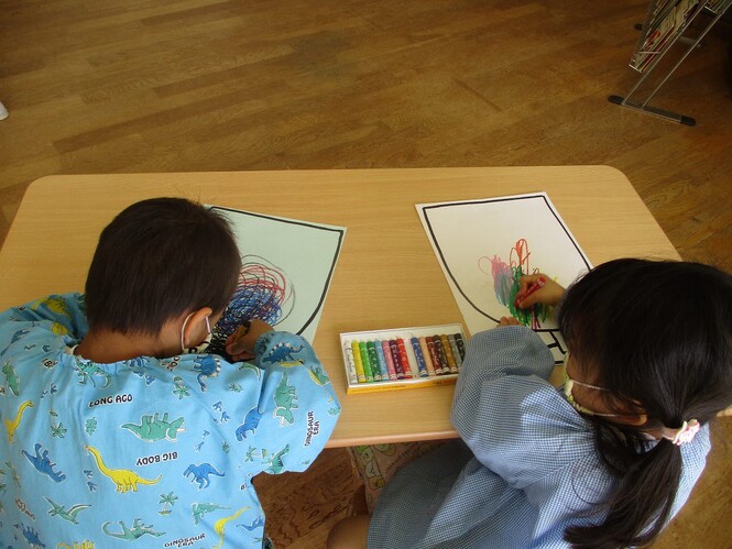 クレパスでジュースを塗る子どもの写真