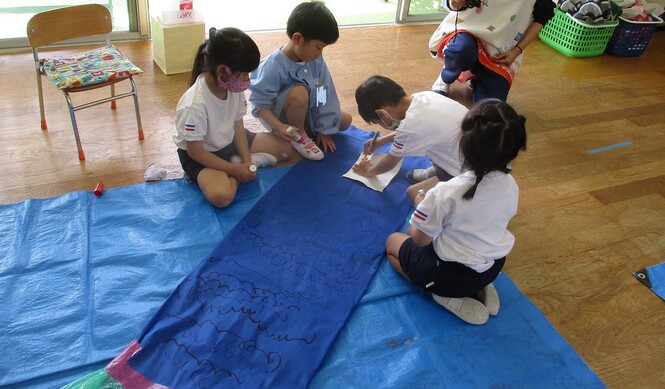 不織布で作ったこいのぼりに、ペンで目を描こうとしている子どもの写真