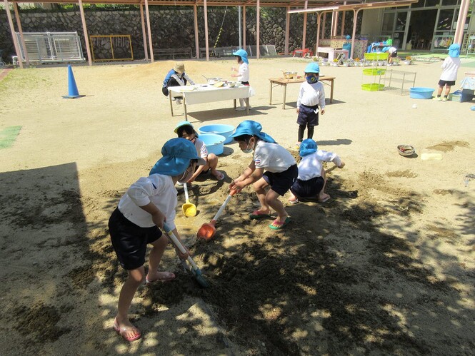 砂場で川を作って遊ぶ子どもの写真