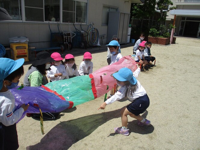 手作りこいのぼりを友達のそばまでいって見せている子どもの写真