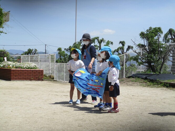 自分たちで作ったこいのぼりを見せている子どもの写真