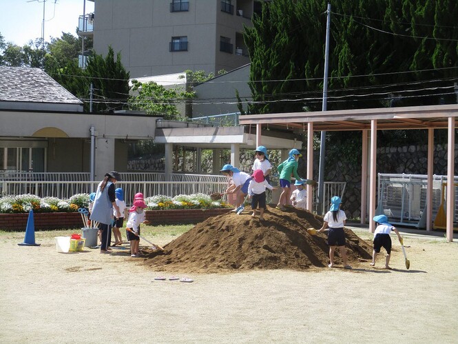 土山に登って喜ぶ子どもの写真