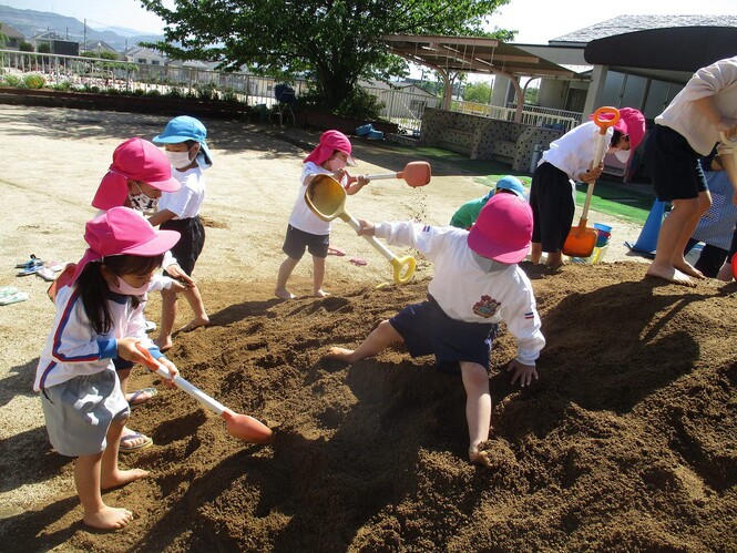 土山の土をスコップで掘る子どもたちの写真