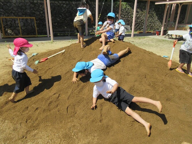 土山の上から転がって遊ぶ子どもの写真