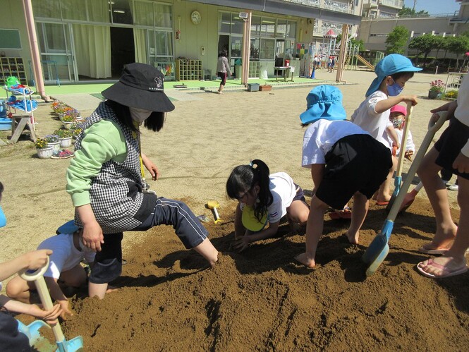 土山の土で、先生の足を隠している子どもたちの写真