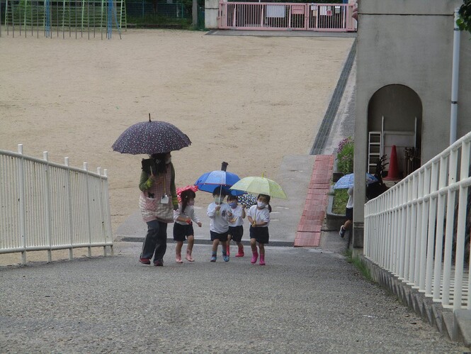 傘をさしてスロープから帰ってくる子どもたちの写真