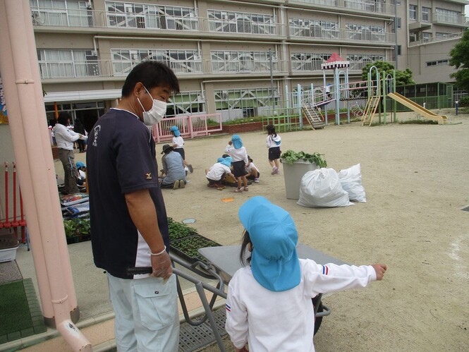 小学校の用務員さんと話をする子どもの写真