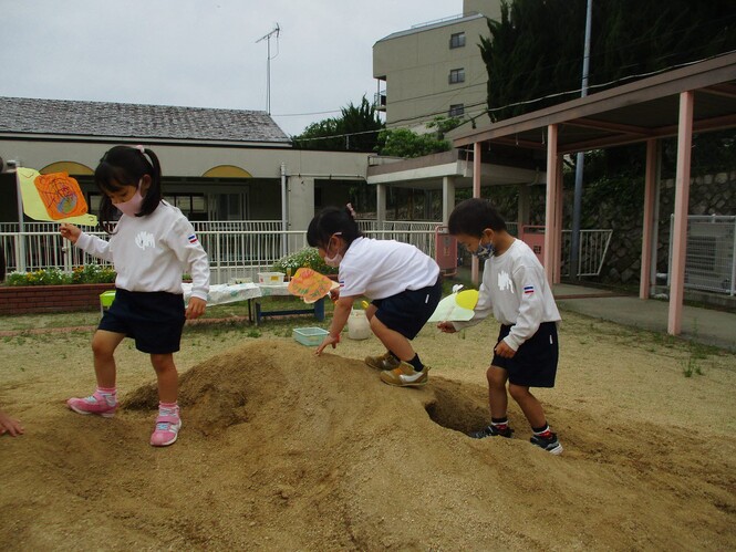 土山の上を、自分が作ったカタツムリのペープサートを散歩させている子どもの写真