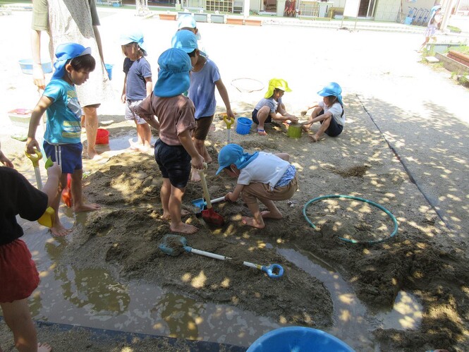 砂場で泥遊びをする子どもの写真