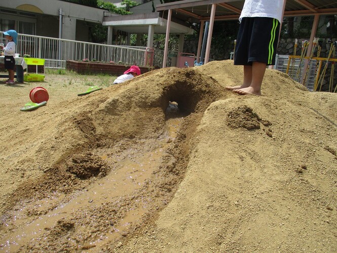 子どもが作った土山のトンネルの写真