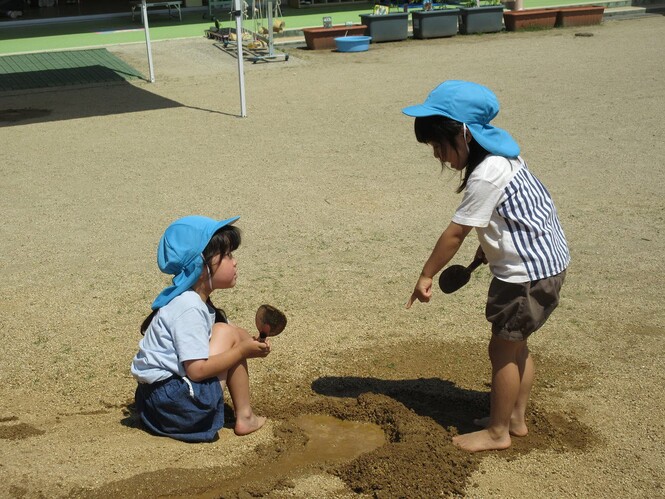 土山から流れてくる水をせき止めようと、盛り土をしている子どもの写真