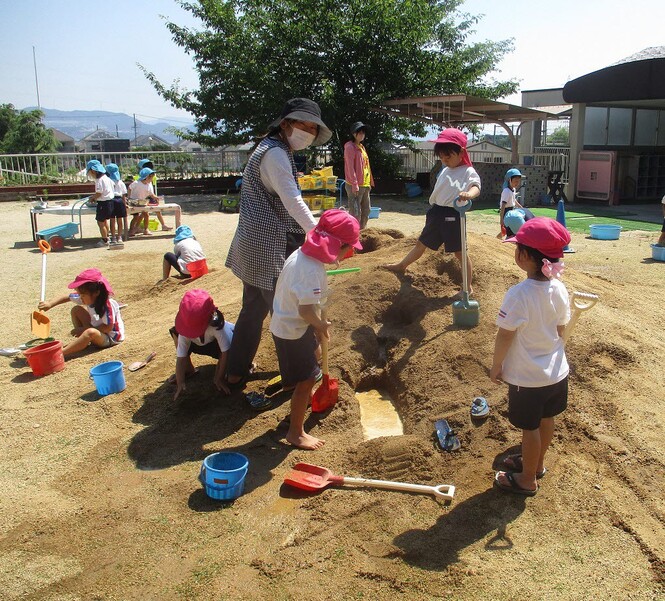 土山で自分たちの作った川をみるもも組子どもの写真