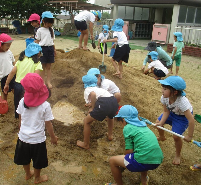 土山で、土で壁をつくって水をためている子どもの写真