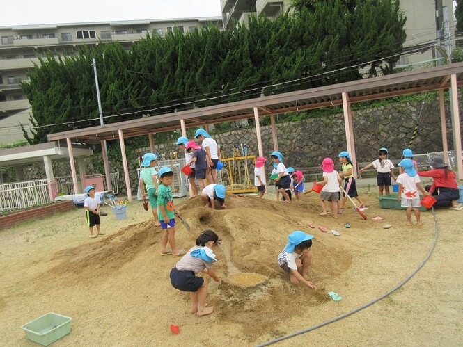 全園児で土山で遊んでいる子どもの写真