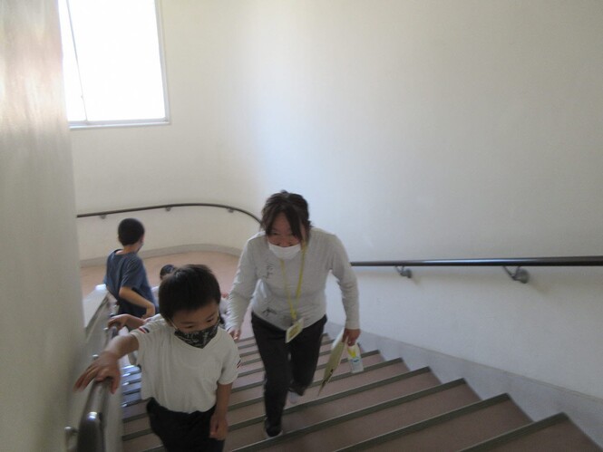 眼科検診をしに、小学校の階段をあがっている先生と子どもの写真