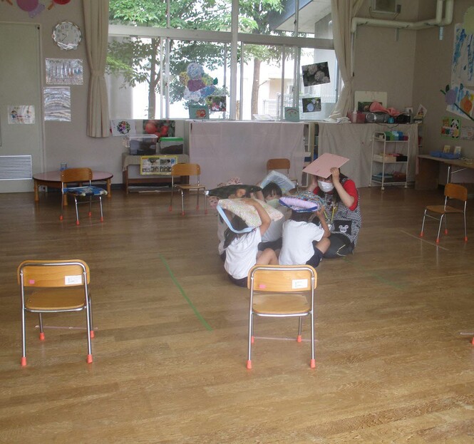 地震の避難訓練で、頭に座布団でかばい部屋で待機している子どもの写真