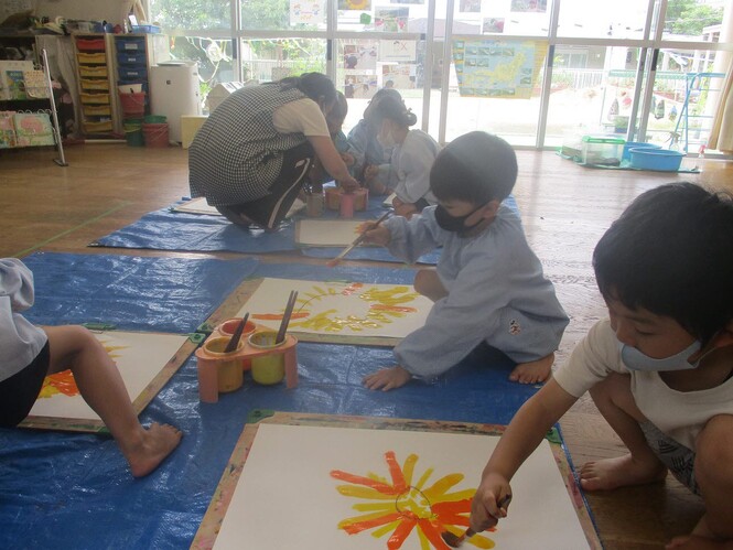 絵具でひまわりを描く子どもたちの写真