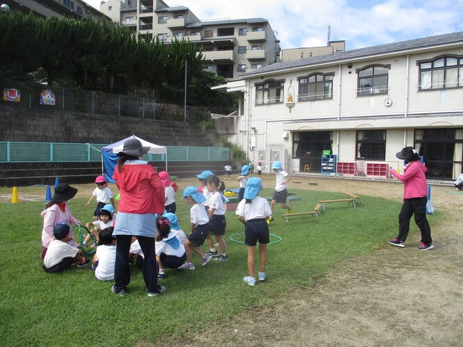 地震の避難訓練で芝生広場の真ん中に集まってきている子どもたちの写真