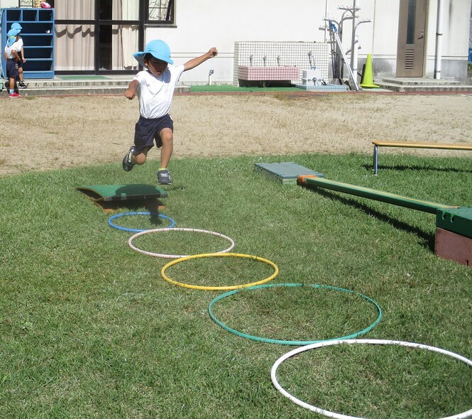 バッタになって、踏切版をつかっておもいきりジャンプする子どもの写真