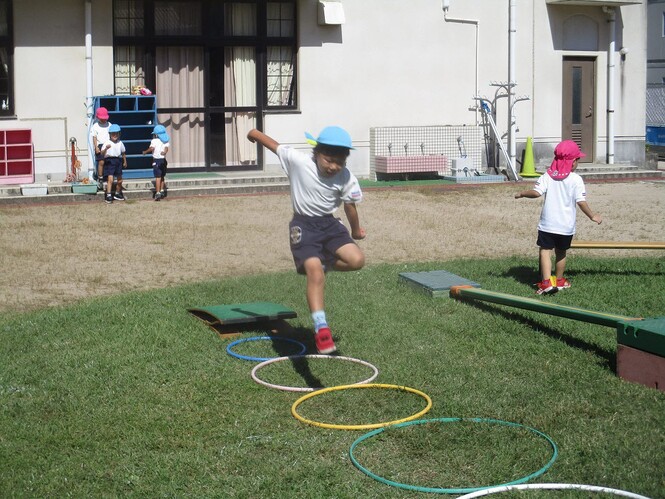 バッタになって、踏切版を使っておもいきりジャンプする子どもの写真