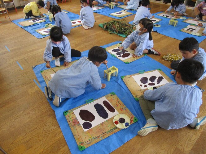 自分で絵の具を混色し、できた色でさつま芋を描いている子どもの写真