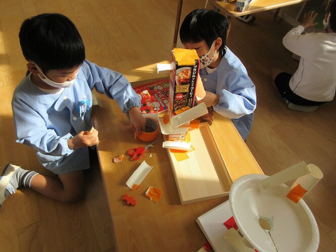 手作りおもちゃを作って遊んでいる子どもの写真