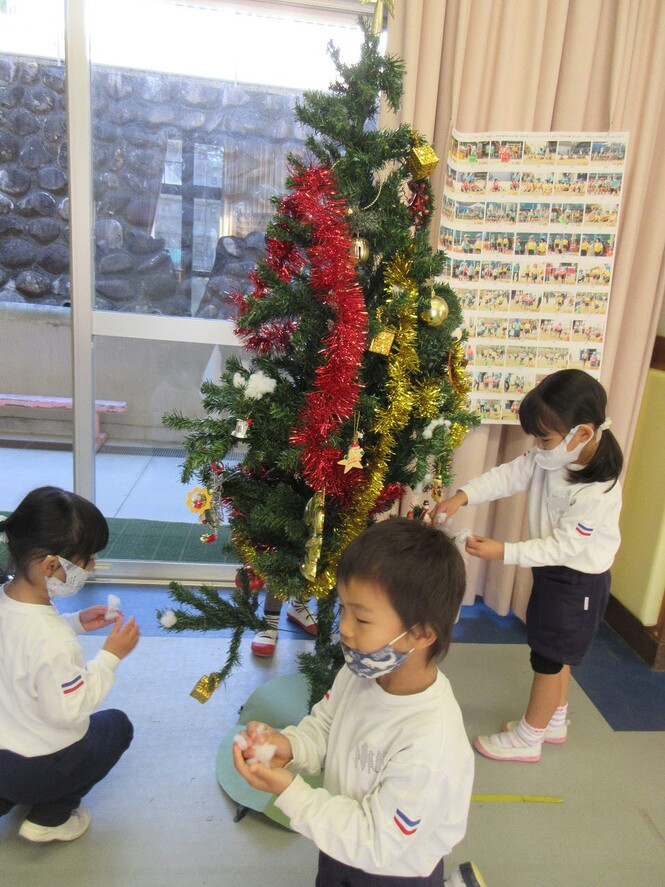クリスマスツリーに飾りをつけるもも組子どもの写真