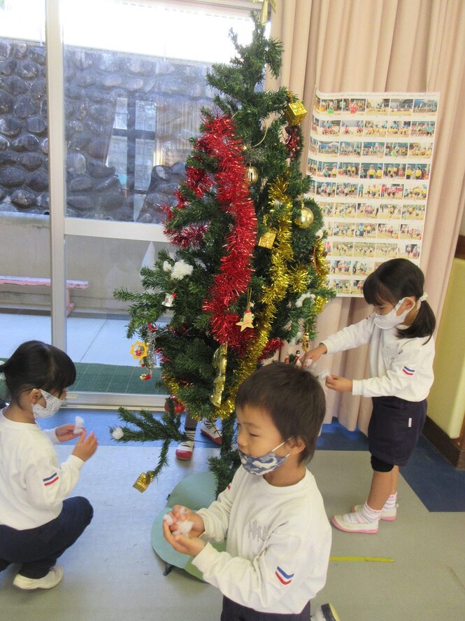 クリスマスツリーに飾りをつけるもも組子どもの写真