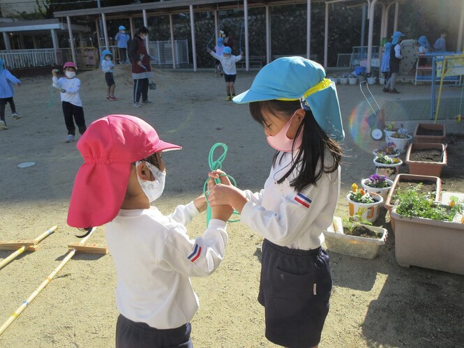 縄跳びの結び方を4歳児に教える5歳児の写真