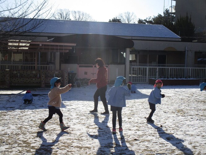 園庭で雪合戦をする子どもと先生の写真