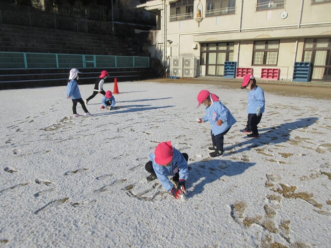 芝生広場の雪を集めるもも組子どもたちの写真