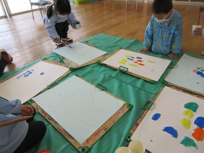アクリル絵の具を使って魚の絵を描いている子どもの写真