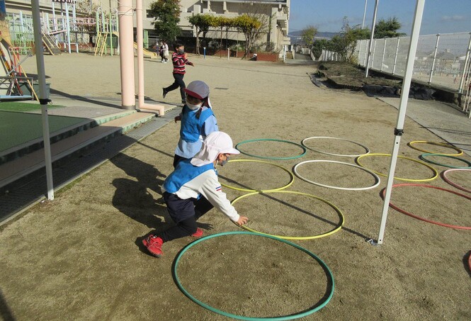 さかなになって、フラフープをあぶくにみたて、とんで遊んでいる子どもの写真