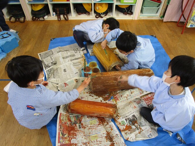 生活発表会で使う小道具の丸太を作っている子どもの写真