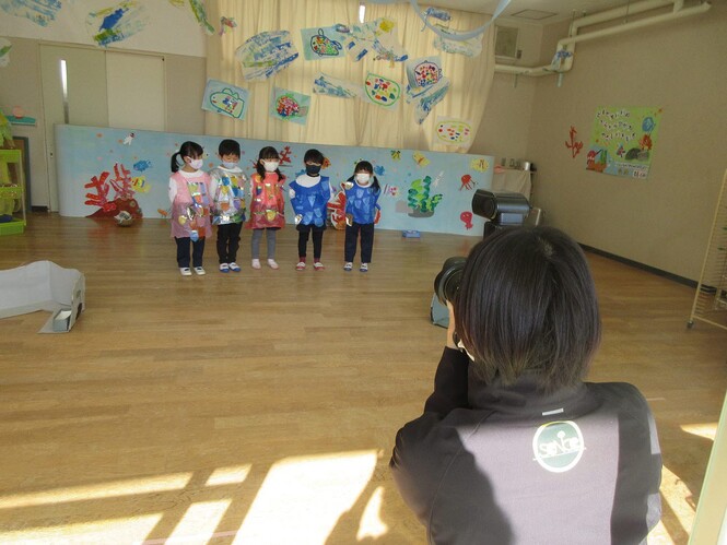 カメラマンに歌を歌っているところをとってもらっている子どもの写真