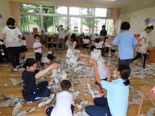 新聞紙で遊んでいる子どもたちの写真