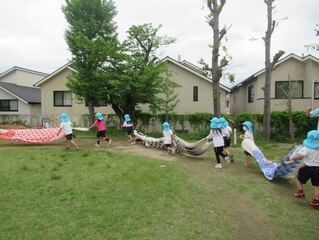 こいのぼりと遊ぶ子どもたちの写真