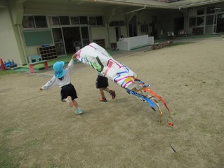 こいのぼりと遊ぶ子どもたちの写真