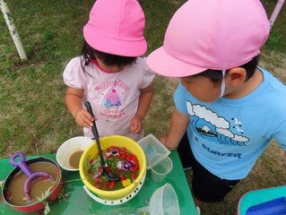 花びらなどでごちそう作りをして遊んでいる子どもたちの写真