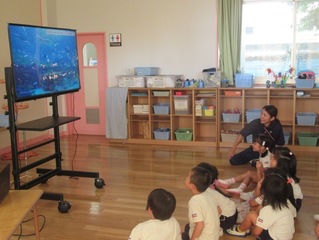 魚の映像を見ている子どもたちの写真