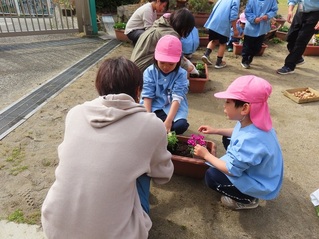 お花を植えている子どもたちの写真