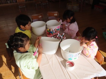 植木鉢に絵を描いている子どもたちの写真