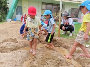 溜まった水に足を入れて楽しんでいる子どもたちの写真