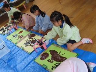 カブトムシの絵を描いている子どもたちの写真